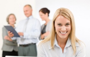 Eine mit ihrer E-Mail-Archivierung zufrieden lächelnde Frau im Vordergrund, zufriedene Kollegen im Hintergrund